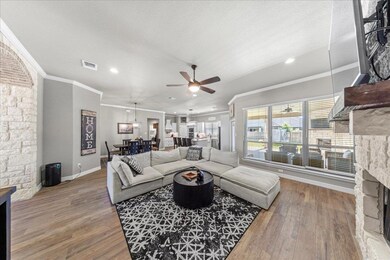 Living room featuring crown molding, a stone fireplace, light wood-style flooring, ceiling fan, and recessed lighting