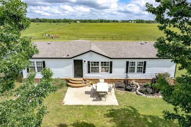 Rear view of house featuring a patio, roof with sh