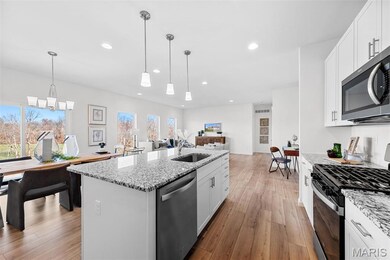 Kitchen featuring stainless steel appliances, white cabinets, light stone countertops, and recessed lighting