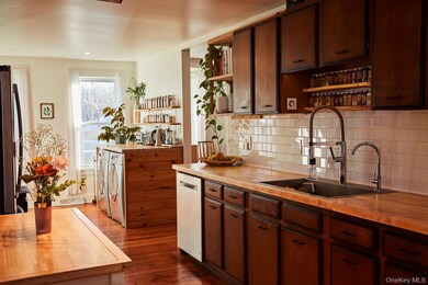Kitchen featuring open shelves, butcher block countertops, dark brown cabinets, and backsplash