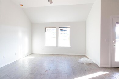 Unfurnished room with light wood finished floors, lofted ceiling, healthy amount of natural light, baseboards, and a smoke detector