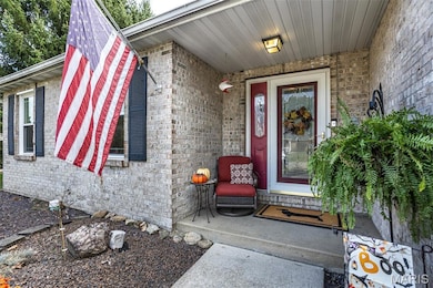 View of exterior entry featuring brick siding and covered porch