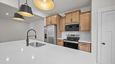 Open concept kitchen with 9-foot white quartz island in two story townhome at Clayton Crossing by DRB Homes in Arden, NC