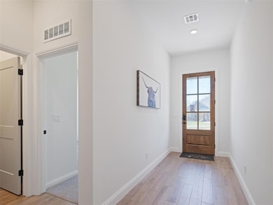 Doorway with light wood-type flooring and baseboards