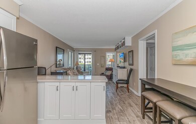 Kitchen with white cabinetry, light wood-type flooring, kitchen peninsula, stainless steel refrigerator, and a kitchen bar