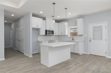 Kitchen with white cabinetry, a center island, decorative light fixtures, stainless steel microwave, and recessed lighting