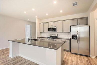 Kitchen with gray cabinetry, a sink, visible vent