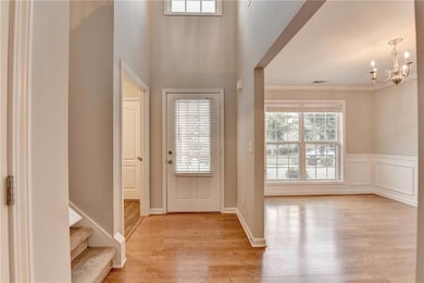 Entryway featuring a chandelier, light wood finished floors, ornamental molding, and stairs