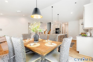 Dining space with light wood-style flooring, stairway, and recessed lighting