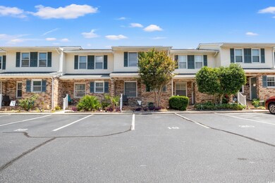 Townhome / multi-family property with uncovered parking and brick siding