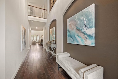 Foyer with dark engineered wood floors, arched wal