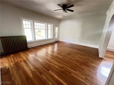Empty room featuring ceiling fan, radiator, hardwood / wood-style flooring, and ornamental molding