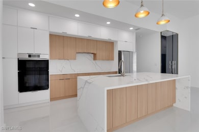 Kitchen featuring modern cabinets, multiple ovens,