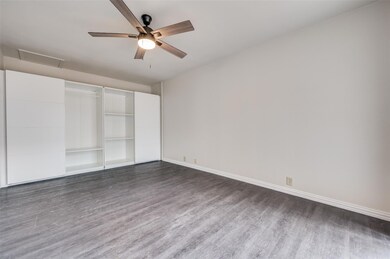 Unfurnished bedroom with ceiling fan, dark hardwoo