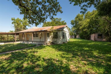 Back of house featuring a porch, a yard, and a car