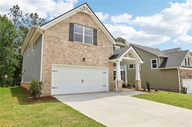View of front of home featuring a garage, brick siding, driveway, and a front lawn