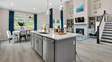Kitchen featuring stainless steel dishwasher, a sink, gray cabinetry, light wood-style flooring, and a glass covered fireplace