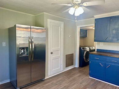 Kitchen featuring blue cabinets, stainless steel fridge with ice dispenser, ornamental molding, dark wood-style flooring, and washer / clothes dryer