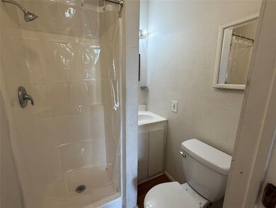 Full bath with a textured wall, a shower with shower curtain, and vanity