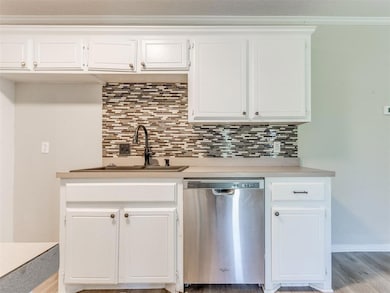 Kitchen featuring dishwasher, a sink, backsplash, and light countertops