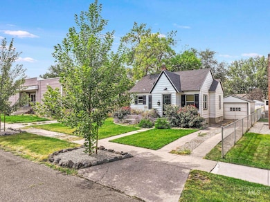 View of front of property featuring a garage, an outdoor structure, a chimney, and a shingled roof
