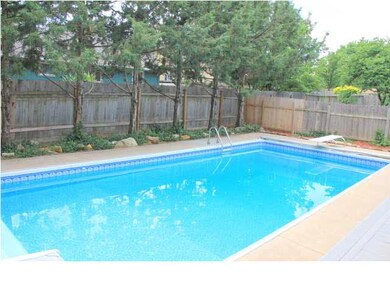 Pool with landscaping and tall wood privacy fence.