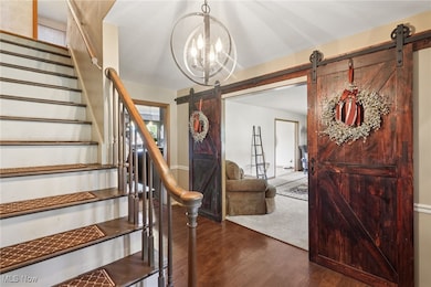 Stairs featuring a barn door, wood finished floors, and a chandelier