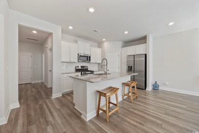 Kitchen featuring tasteful backsplash, stainless steel appliances, white cabinets, a breakfast bar area, and light stone counters