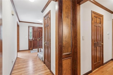 Corridor featuring ornamental molding, light wood finished floors, and baseboards