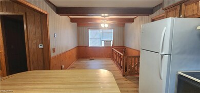 Kitchen with beamed ceiling, white fridge, and light wood-type flooring