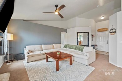 Carpeted living room with vaulted ceiling, arched walkways, and a ceiling fan