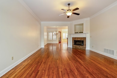 Unfurnished living room with a chandelier, ornamental molding, wood finished floors, a premium fireplace, and ceiling fan
