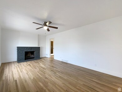 Unfurnished living room featuring a fireplace with flush hearth, light wood-type flooring, and ceiling fan