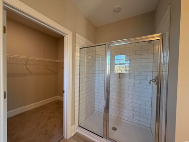 Full bath featuring a stall shower, a walk in clos