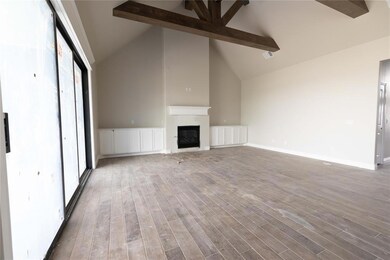 Unfurnished living room featuring beam ceiling, a glass covered fireplace, wood finished floors, high vaulted ceiling, and baseboards