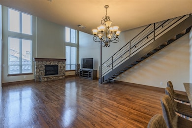Living area featuring a fireplace, dark wood-style floors, stairs, a chandelier, and a towering ceiling
