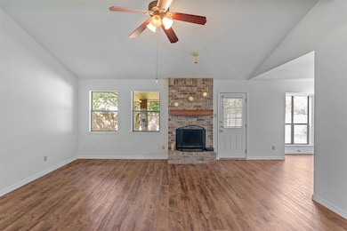 Unfurnished living room with vaulted ceiling, a fireplace, wood finished floors, and plenty of natural light