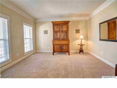 Living Room is across the Foyer from the Dining Room and has carpet and crown molding.