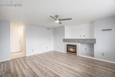 Unfurnished living room with ceiling fan, light wood-type flooring, a tiled fireplace, and baseboards