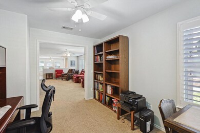 Carpeted office featuring ceiling fan