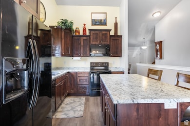 Kitchen with black appliances, light countertops, light wood-type flooring, and a center island