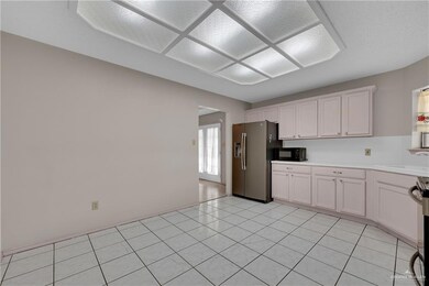 Kitchen with stainless steel appliances, white cabinetry, sink, and light tile patterned flooring