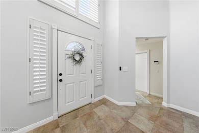 Foyer entrance with baseboards and a towering ceiling