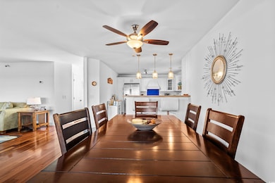 Dining space featuring ceiling fan and dark wood-style flooring