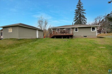 Rear view of house with a wooden deck and a yard