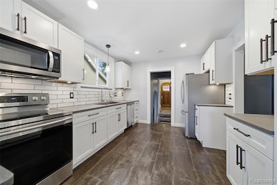Kitchen featuring stainless steel appliances, tasteful backsplash, white cabinets, and recessed lighting