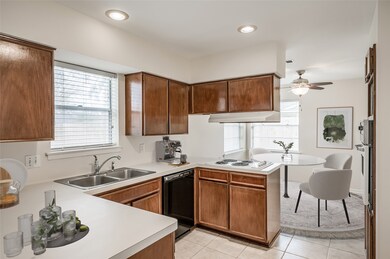 Kitchen is open to Den and Dining Room seen in background. Kitchen has cooktop & separate wall oven. Tile floors continue through these areas.  PHOTOS VIRTUALLY STAGED.