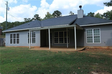 Rear view of house with a patio area, a lawn, and a chimney