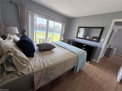 Bedroom featuring access to outside, wood finished floors, a textured ceiling, and baseboards