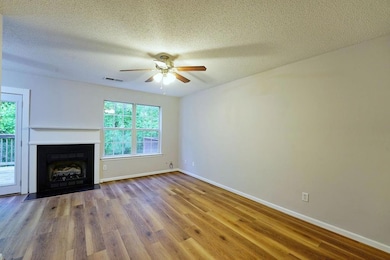 open concept living room featuring plenty of natural light, ceiling fan, wood finished floors, and a fireplace with flush hearth